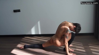 Татуированная голая фитнес тренерша гнется во время йоги